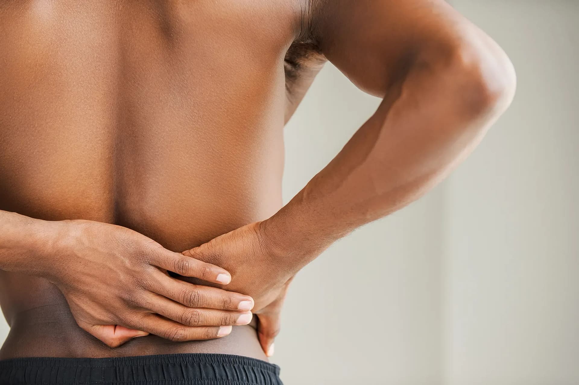 A person holds their lower back with both hands