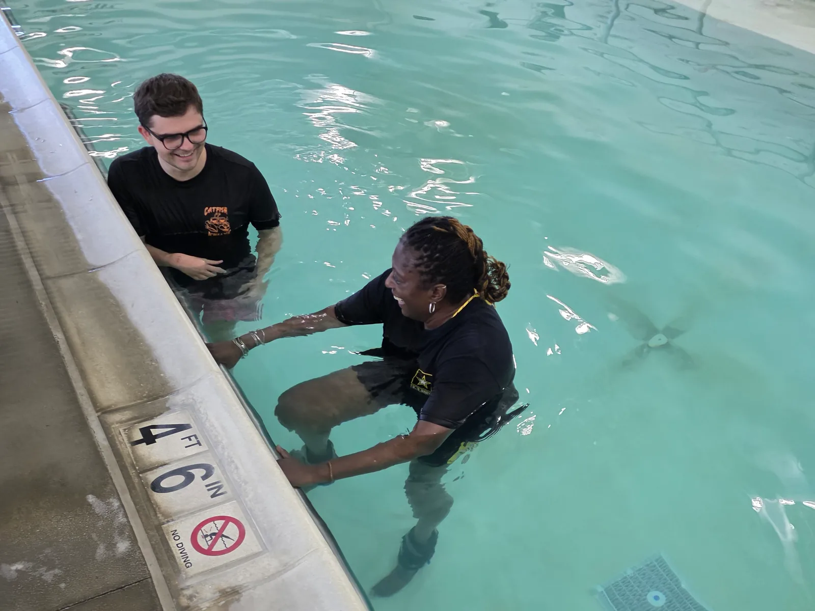 Two people work together at the edge of the Caroline therapy pool.