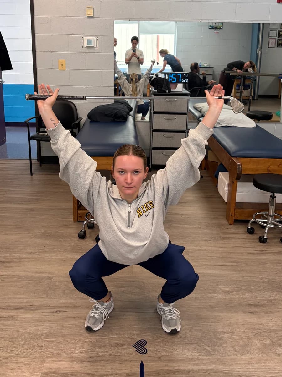 Overhead squat movement screening with a golf club.